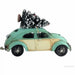 A vintage-style mint green and cream Volkswagen Beetle ornament or decoration with a small snow-dusted Christmas tree strapped to the roof, shown on a plain white background.