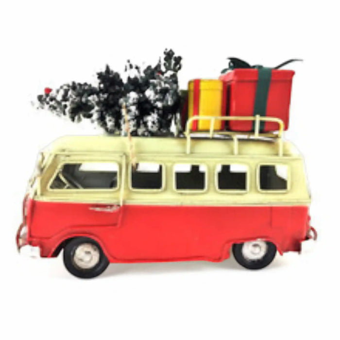 A vintage-style toy or model van in red and cream, shown from the side on a white background, with a black-and-white tree and red and yellow luggage strapped to its roof rack.