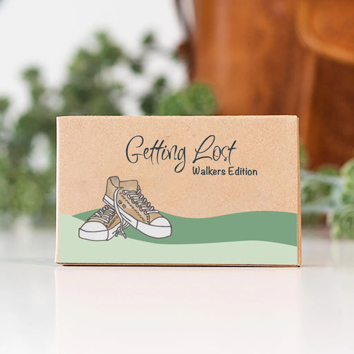 Box labeled 'Getting Lost Walkers Edition' with a shoe illustration on a blurred natural background