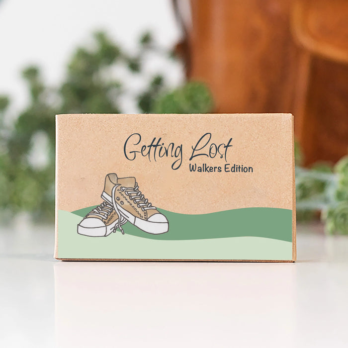 Box labeled 'Getting Lost Walkers Edition' with a shoe illustration on a blurred natural background