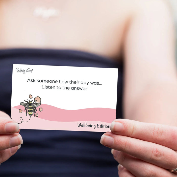 Hand holding a card with a bee illustration and text on a blurred background
