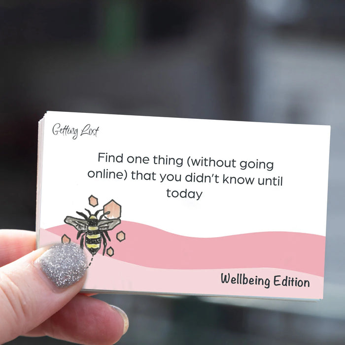 Card with a bee illustration and text held by a hand, on a blurred background