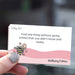 Card with a bee illustration and text held by a hand, on a blurred background