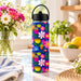 Wild Joy 620ml insulated water bottle with bright floral artwork on blue, styled on a kitchen bench beside flowers and citrus fruit.