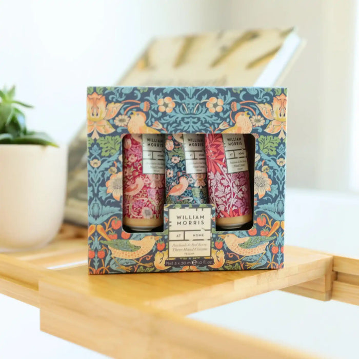 Set of three small bottles in a decorative box with floral design on a wooden surface.