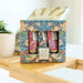 Set of three small bottles in a decorative box with floral design on a wooden surface.