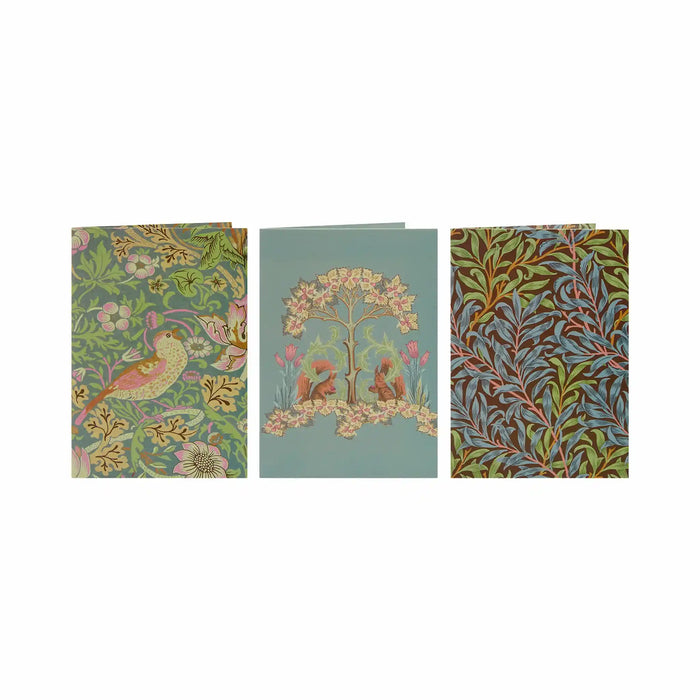 Three William Morris style patterned cards or envelopes displayed side by side on a white background, featuring floral, bird, and leaf motifs in muted green, blue, pink, and gold tones.